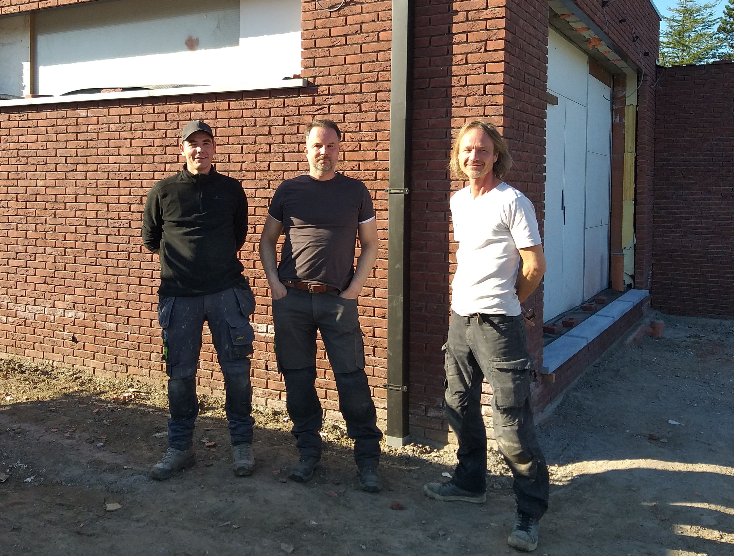 3 mannen poseren voor een net gerenoveerd huis